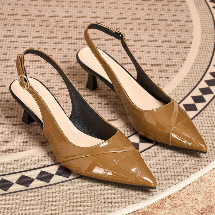 A pair of pointed-toe slingback pumps in a glossy tan patent leather with a subtle embossed pattern, resting on a textured beige rug with a black and beige geometric border.