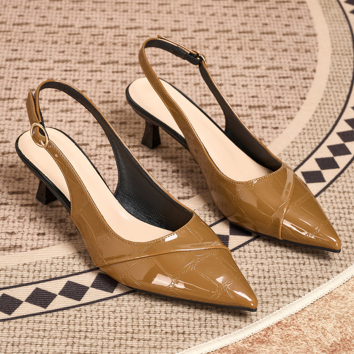 A pair of pointed-toe slingback pumps in a glossy tan patent leather with a subtle embossed pattern, resting on a textured beige rug with a black and beige geometric border.