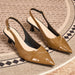 A pair of pointed-toe slingback pumps in a glossy tan patent leather with a subtle embossed pattern, resting on a textured beige rug with a black and beige geometric border.