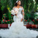 Woman in a white wedding dress holding a bouquet of flowers, standing in a garden setting.