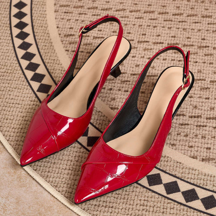 A pair of glossy red slingback pointed-toe pumps with low block heels, displayed on a textured beige and black patterned rug.