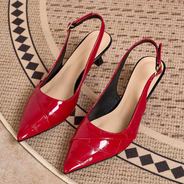 A pair of glossy red slingback pointed-toe pumps with low block heels, displayed on a textured beige and black patterned rug.