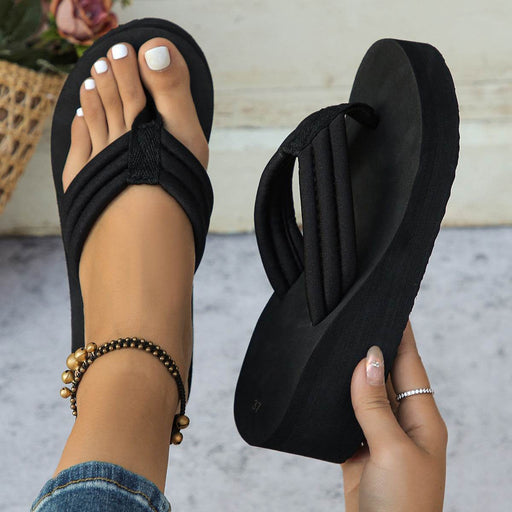 Black flip-flop sandal being held with a blurred background