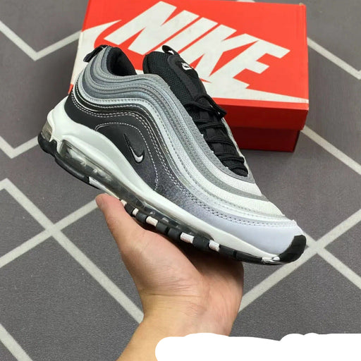 Black and gray sneaker held in a hand with a red Nike box in the background