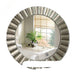 Round wall mirror with decorative silver frame reflecting a bathroom interior.