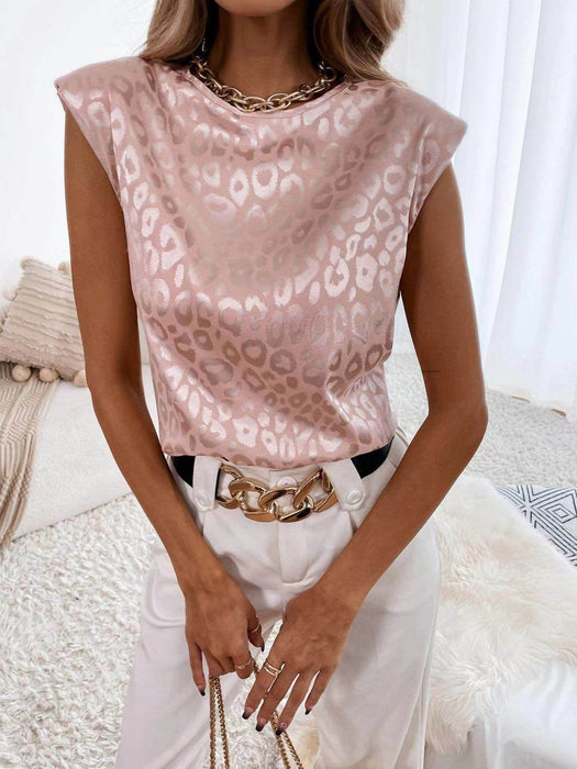 Person wearing a pink leopard print top with white pants and a gold chain belt.