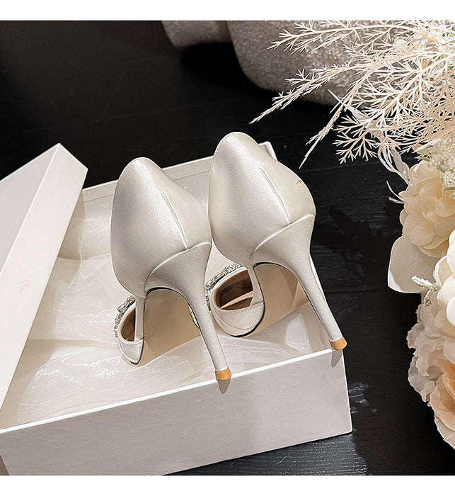 Pair of white high-heeled shoes with gold accents on a white box against a dark background.