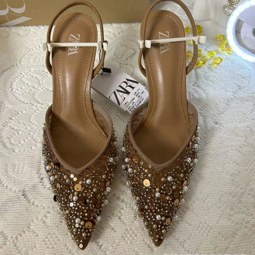 Pair of embellished pointed-toe shoes with a Zara tag on a textured surface.