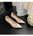 Beige high-heeled shoes on a dark surface with a white flower arrangement.