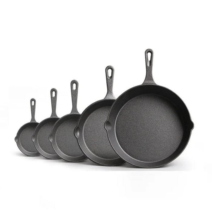 Set of six black cast iron skillets of different sizes on a white background