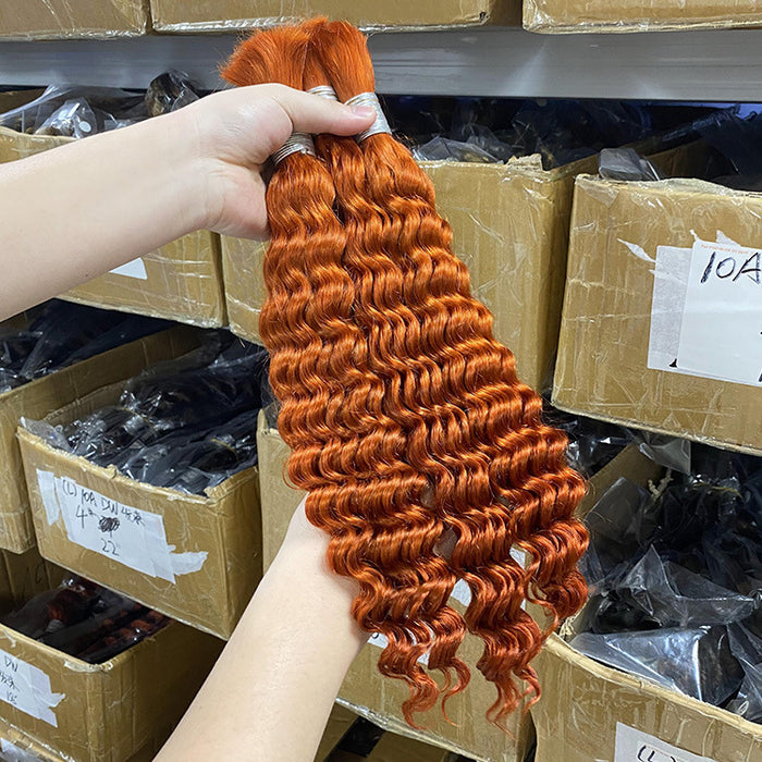 Person holding a bundle of orange hair extensions with boxes in the background