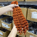 Person holding a bundle of orange hair extensions with boxes in the background
