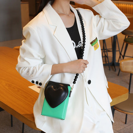 Person wearing a white blazer with a black and green bag in an indoor setting