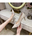 High-heeled shoes being held in front of a mirror with decorative elements.