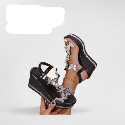 Black wedge sandals with floral designs held by a hand on a light gray background
