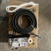 Unboxed electronic components including a black cable, white tube, and remote control on a cardboard box.
