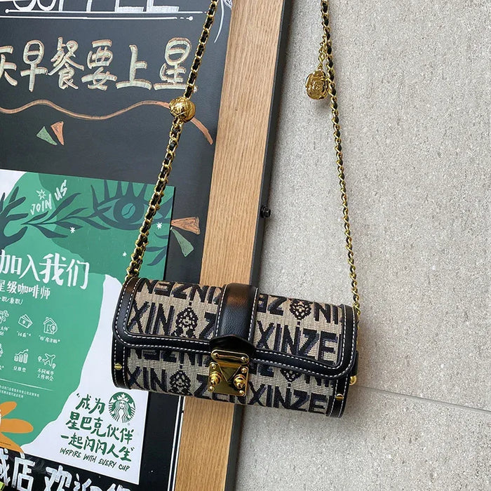 Designer handbag with gold chain strap on a textured surface