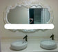 Decorative mirror with intricate frame above two ceramic sinks in a bathroom setting.