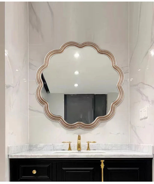 Bathroom vanity with a decorative mirror and gold fixtures.