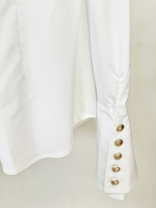 White shirt with gold buttons on a light beige background