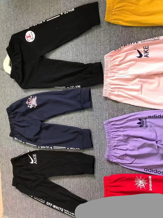 Various pairs of pants with brand logos on a gray surface