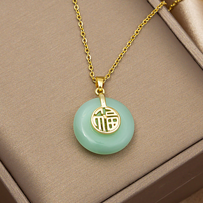 Gold chain necklace with a round light green jadeite pendant featuring a gold Chinese character charm, displayed on a beige jewelry box.