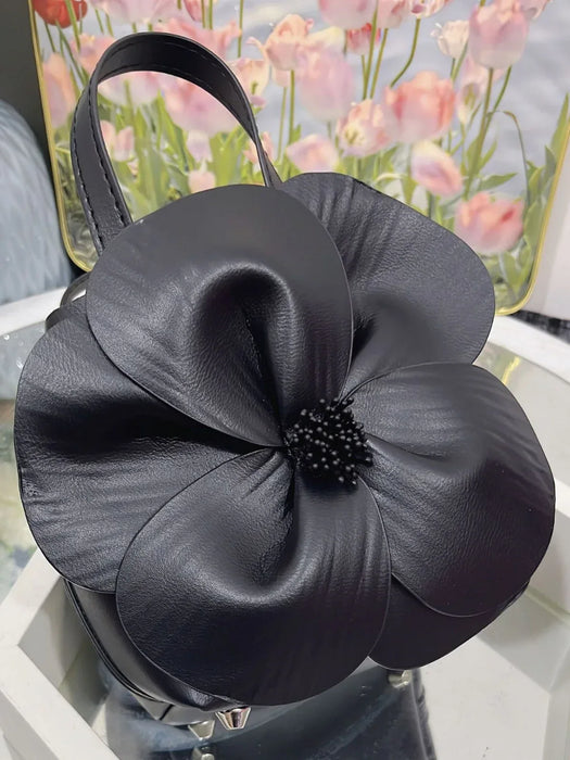 Black leather handbag with a large flower design on a floral background