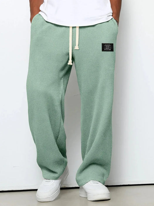 Green textured sweatpants with a white label on a plain background