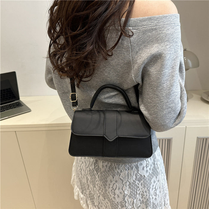 A woman from behind wearing a gray off-the-shoulder sweatshirt and white lace skirt, carrying a small black leather top-handle handbag on her back.