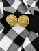 Gold circular earrings on a black and white checkered fabric background