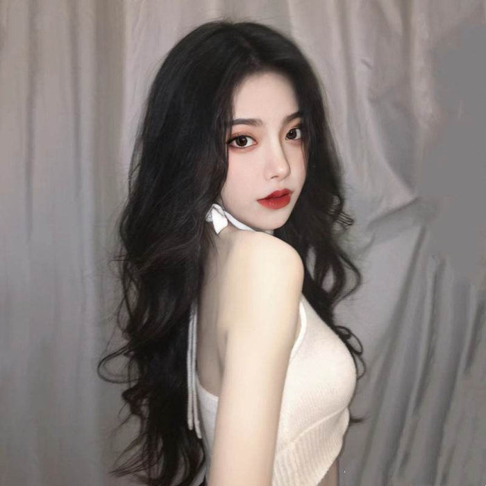 Woman with long dark hair wearing a white top against a neutral background