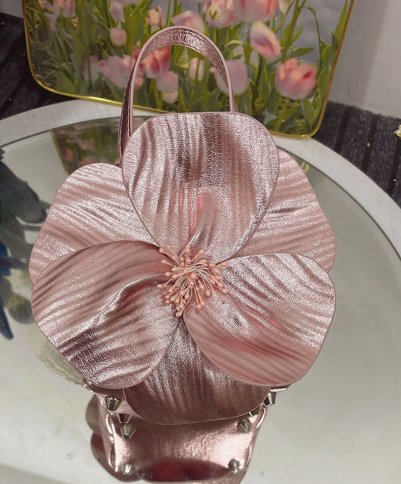 Rose gold handbag with floral design on a reflective surface