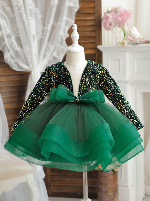Green sequin dress with a large bow on a mannequin against a neutral background