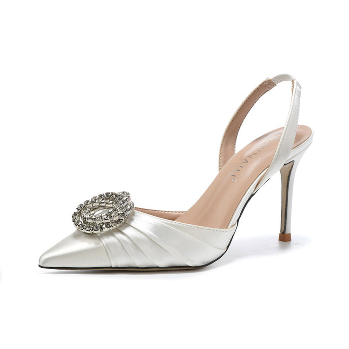 Silver high-heeled shoe with a decorative brooch on a white background