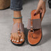 Pair of brown sandals with decorative straps on a gray floor.