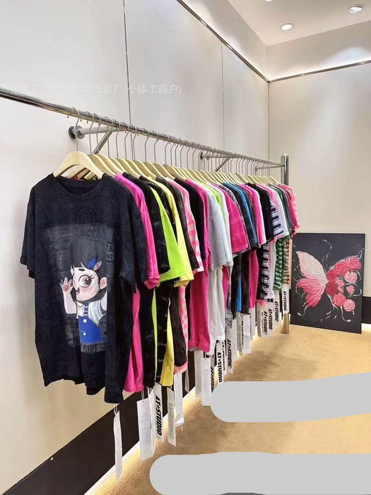 Row of colorful t-shirts on hangers against a white wall.