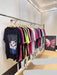 Row of colorful t-shirts on hangers against a white wall.