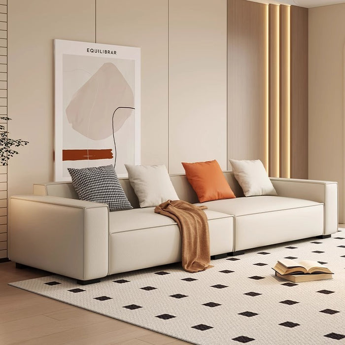 Modern living room with a beige sofa, decorative pillows, and a stylish rug.