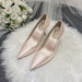 Pair of pink high-heeled shoes on a white fur surface with a bouquet of white roses.