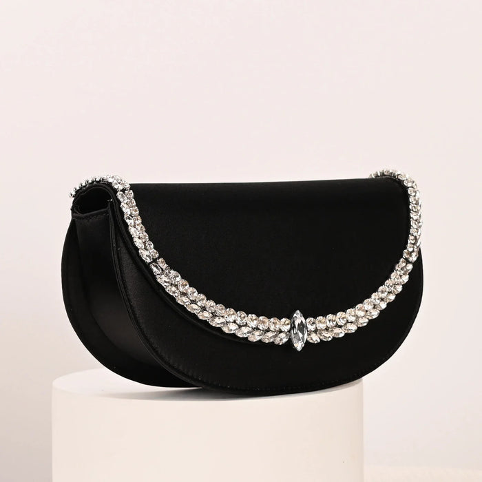 Black handbag with silver embellishments on a light pink background