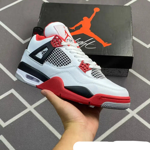 White, black, and red sneaker held in front of a Jordan box on a tiled floor.