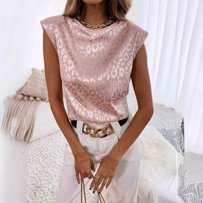 Woman wearing a pink leopard print top with white pants and a gold belt, sitting on a white couch.