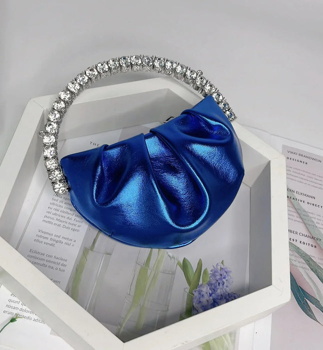 Blue handbag with a decorative handle on a white surface with floral and text background