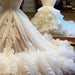 Close-up of a white wedding dress with intricate details and a long train.