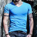 Person wearing a blue t-shirt leaning against a stone wall.