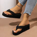 Black wedge sandals worn with light blue jeans on a beige background