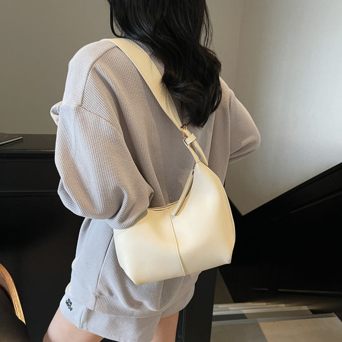 A woman wearing an oversized light gray textured sweatshirt and shorts, shown from the back while carrying a cream-colored shoulder bag.