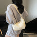 A woman wearing an oversized light gray textured sweatshirt and shorts, shown from the back while carrying a cream-colored shoulder bag.