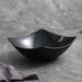 Black ceramic bowl with dimensions on a gray background