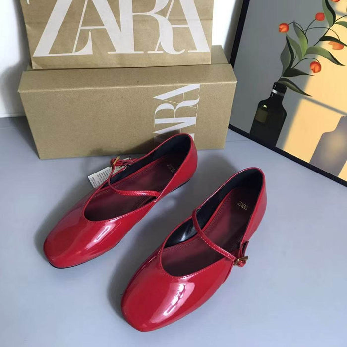 Red shoes with a Zara box on a light gray surface.